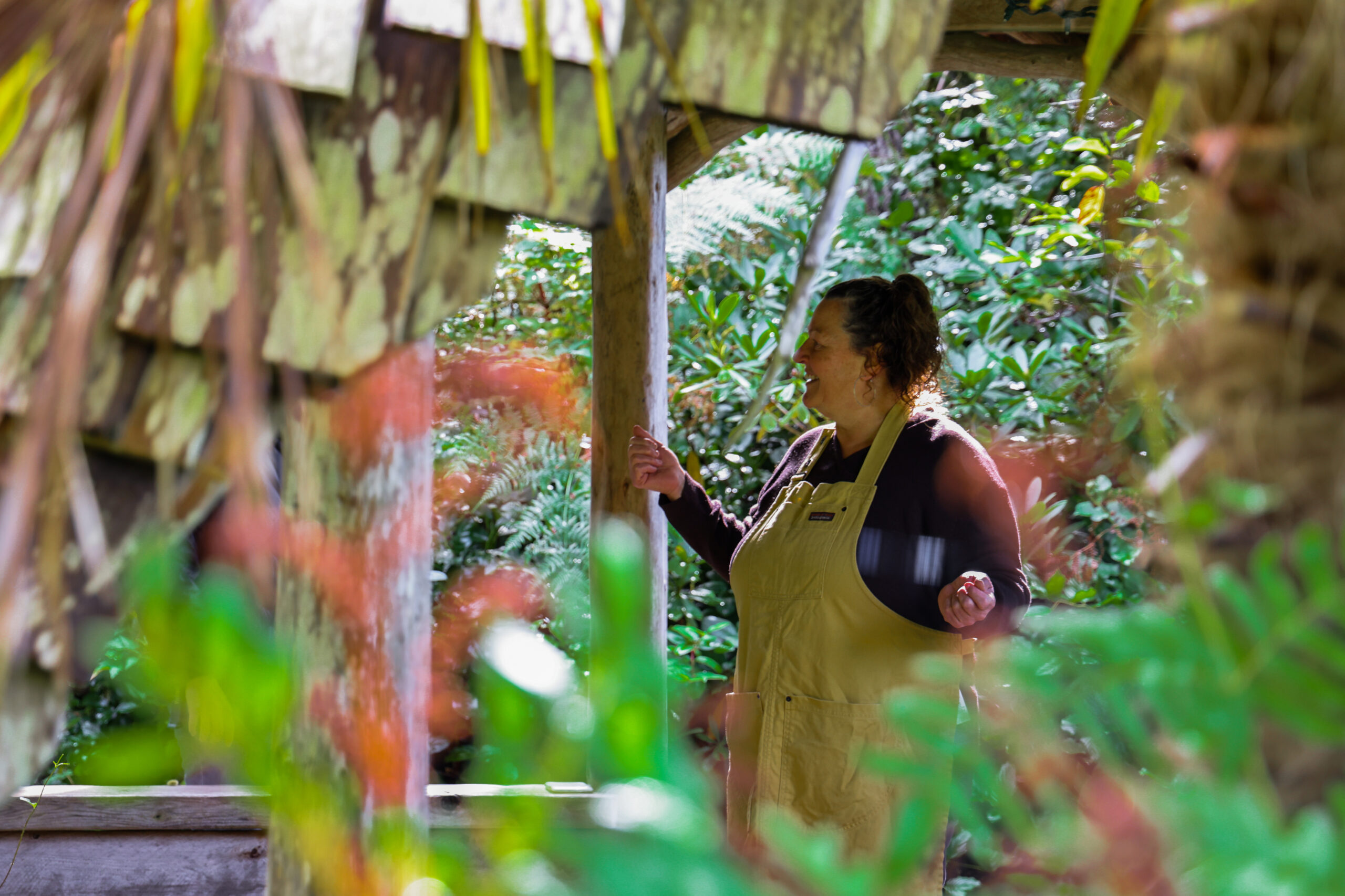 a woman in an apron standing under a wooden structure