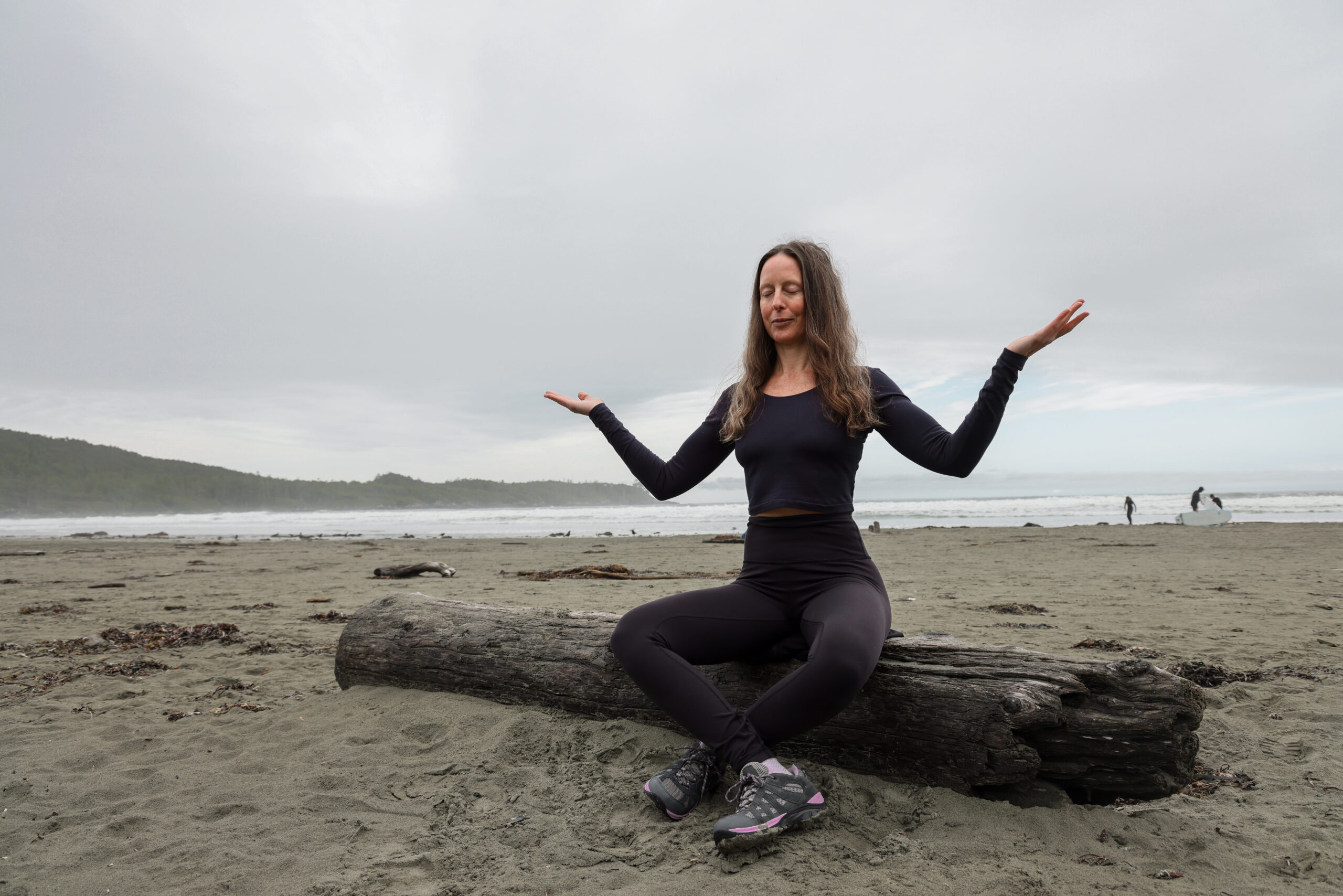 a woman sitting on a log on a beach