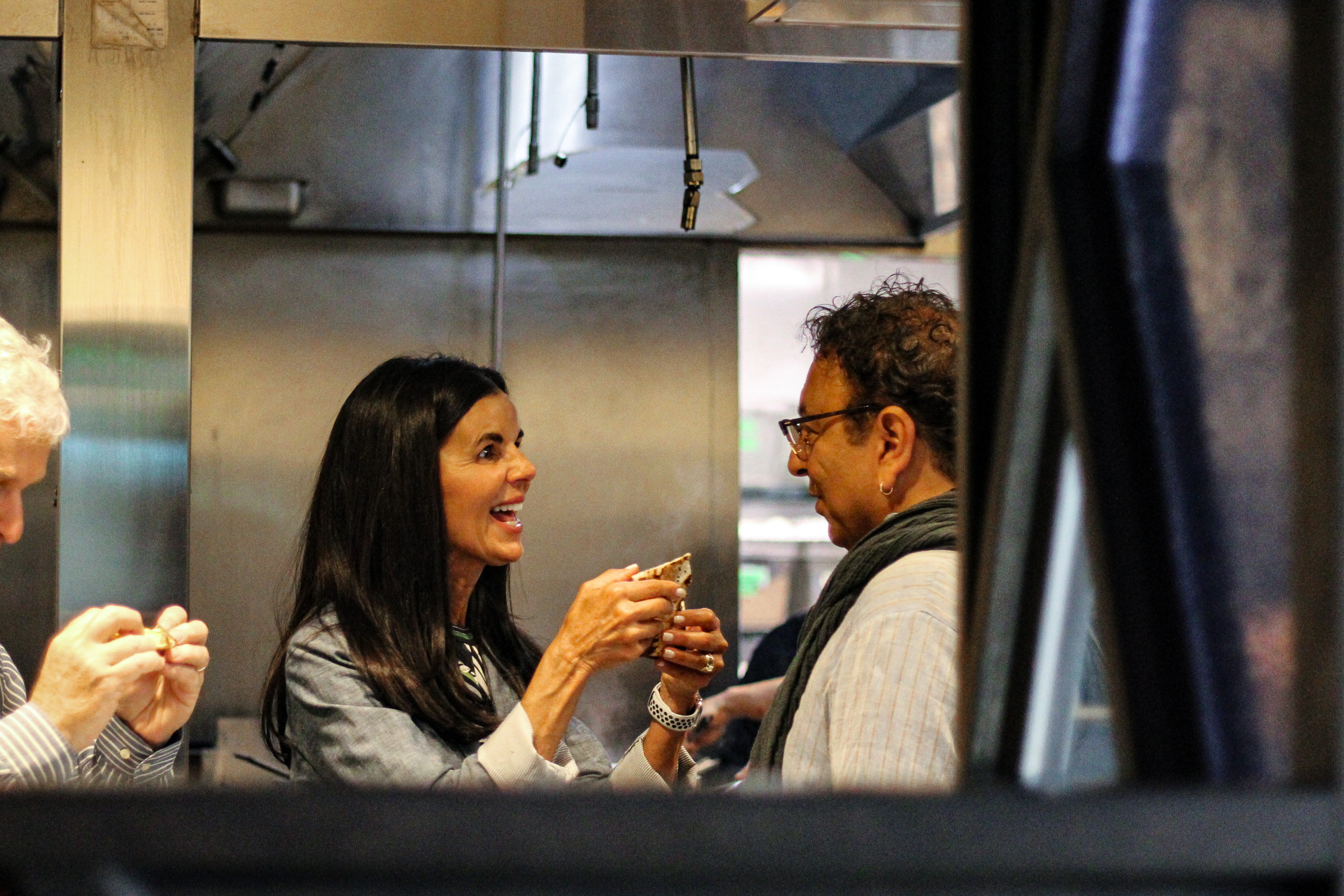 a woman holding a bowl and celebrity chef Vikram Vij in a kitchen